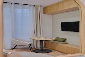 Enjoy a compact living space with a round dining table, two chairs, and a bench featuring a flat-screen TV.