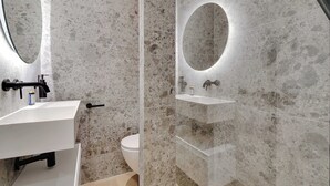 A modern bathroom with a white sink, a toilet, and a mirror with a circular light. - Modern studio - 2P - Clignancourt (Paris)