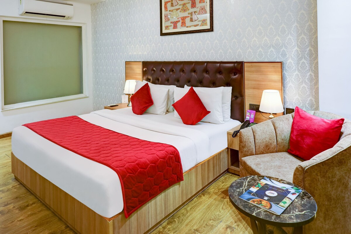 Une chambre d’hôtel avec un grand lit, un petit canapé, une table ronde et un climatiseur fixé au mur.