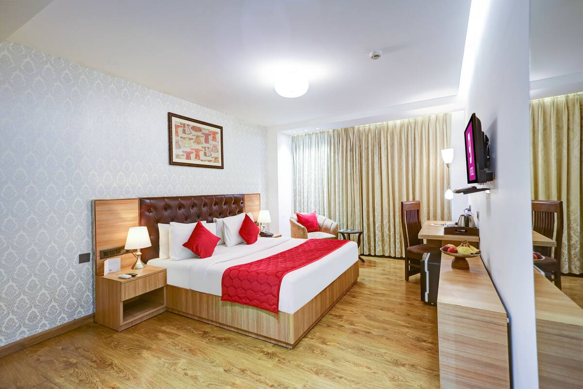 Hotelkamer met een groot bed, nachtkastjes, een bureau, een stoel, een televisie en gordijnen.