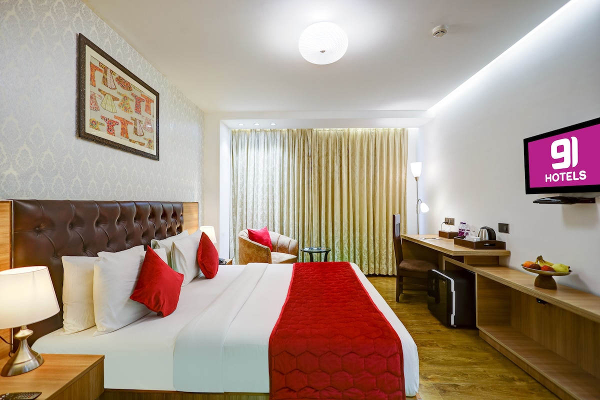A hotel room with a bed, a desk, a TV, and a dining area.