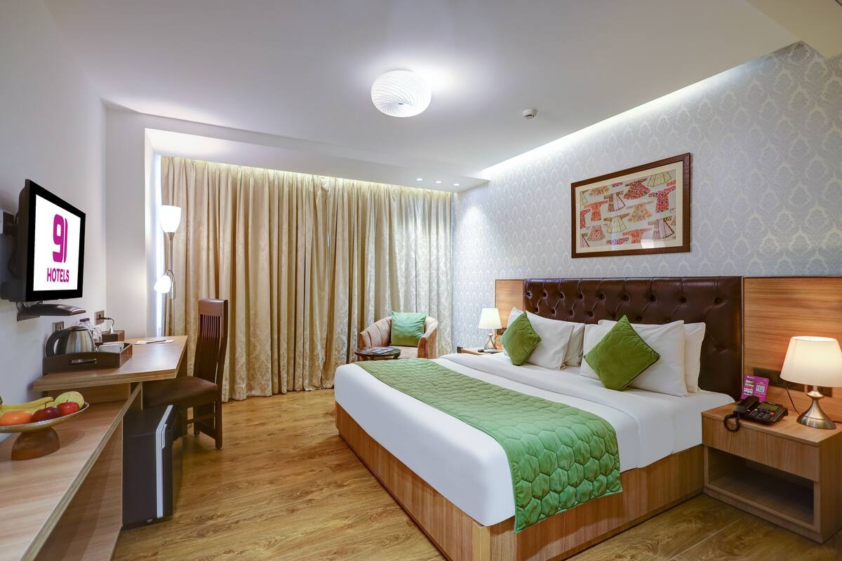 Hotelkamer met een bed, een bureau, een stoel, een televisie en een aan de muur hangend schilderij.