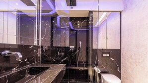 Une salle de bain moderne avec une douche à parois de verre, un meuble-lavabo en marbre et des toilettes.