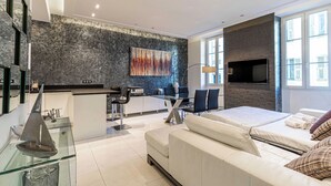 Une chambre d’hôtel moderne dotée d’un grand lit, d’un coin repas et d’un téléviseur fixé au mur.
