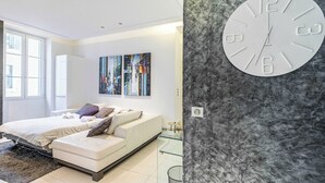 Une chambre à coucher moderne avec un lit, un canapé et des œuvres d’art abstraites accrochées au mur.