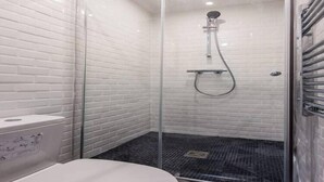 A bathroom with a glass-enclosed shower, white tiled walls, and a white toilet. - Cosy apartment - 4P - Place de la Bastille (Paris)