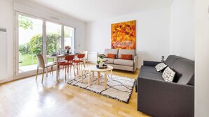 Una sala de estar moderna con comedor, un sofá gris y un cuadro abstracto grande en la pared.