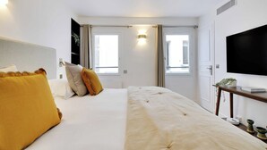 Une chambre d’hôtel avec un lit, des rideaux, une télévision et une petite table sur laquelle est posée une plante.