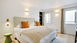 Une chambre à coucher avec un grand lit, deux lampes de chevet, une table de chevet verte et une fenêtre avec des rideaux.