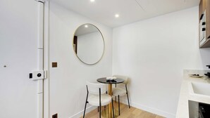 Une cuisine compacte avec une table ronde, deux chaises, un miroir rond et un évier encastré.