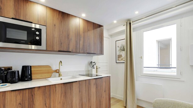 Une cuisine moderne avec des meubles en bois, un four à micro-ondes encastré et un évier.