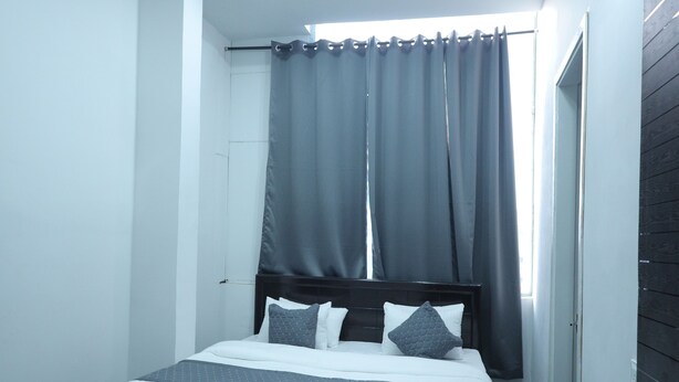 A modern bedroom with a bed, curtains, a ceiling fan, and a black rug. - Atithi Hotel and Dhaba (Panipat)