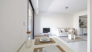 Ein modernes Wohnzimmer mit Essbereich, einer Couch und einer Küche im Hintergrund.
