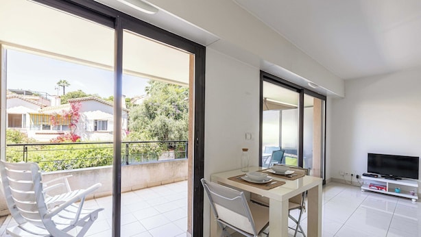 Ein modernes Apartment mit Balkon, Essbereich und Fernseher.
