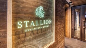 A wooden wall with a neon sign for 'STALLION EXCLUSIVE LODGE'. - Luxurious 4-room apartment with swimming pool, gym, spa and parking (Megève)