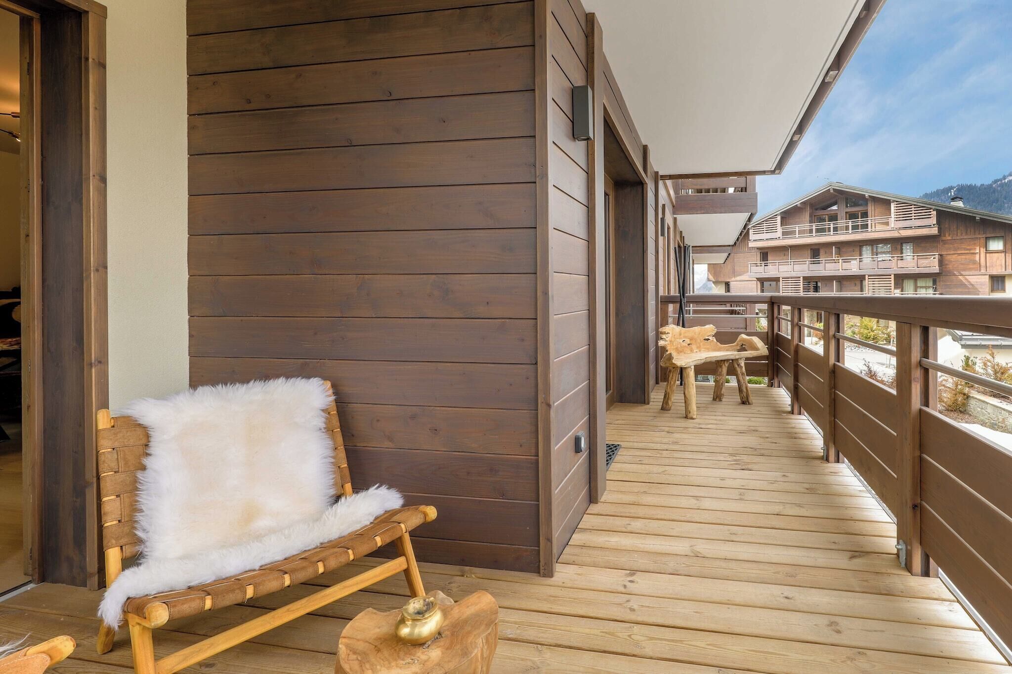 A wooden deck with a bench and a table, overlooking a mountainous landscape.