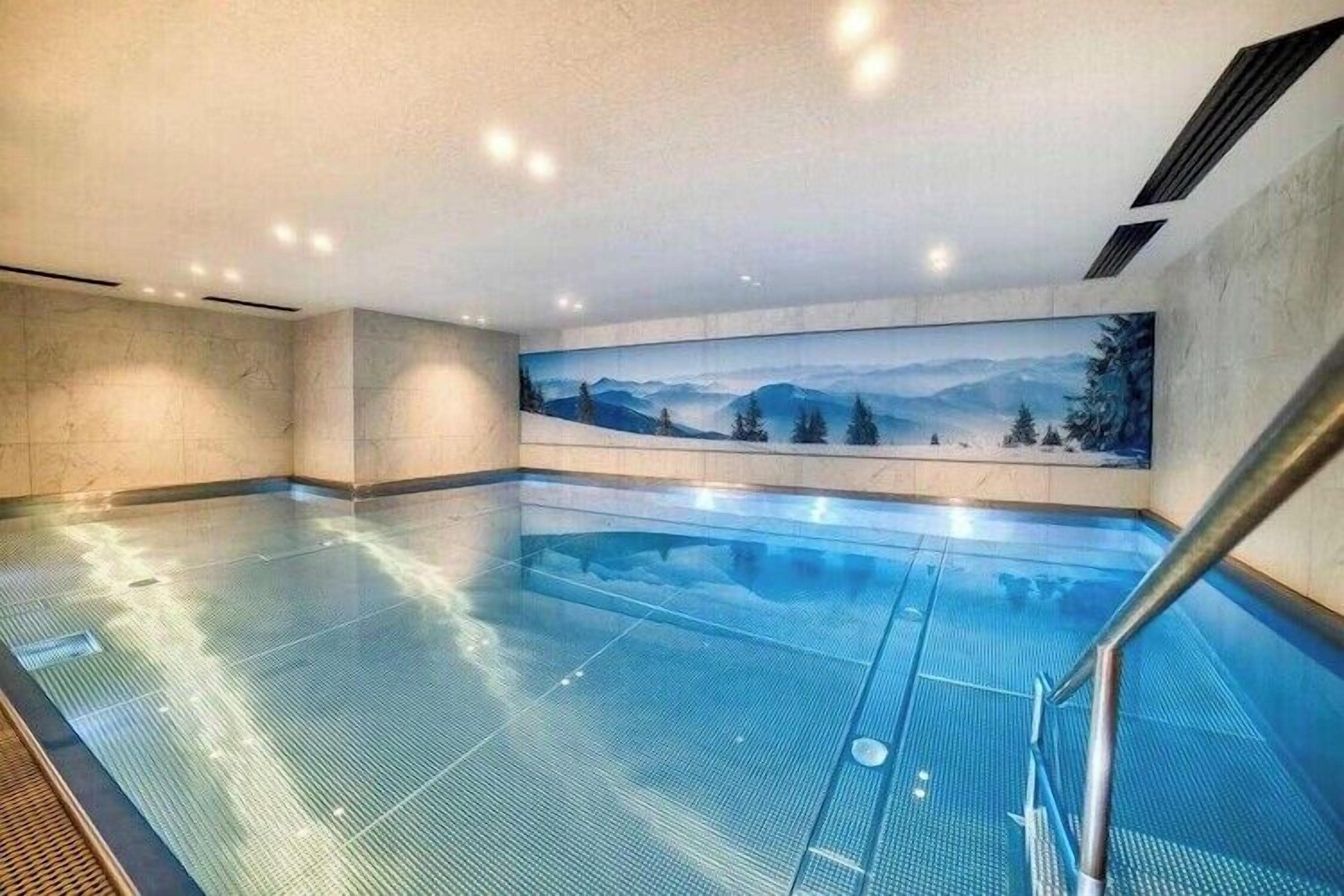 Une grande piscine intérieure avec une vue sur les montagnes, grâce à une vaste baie vitrée.