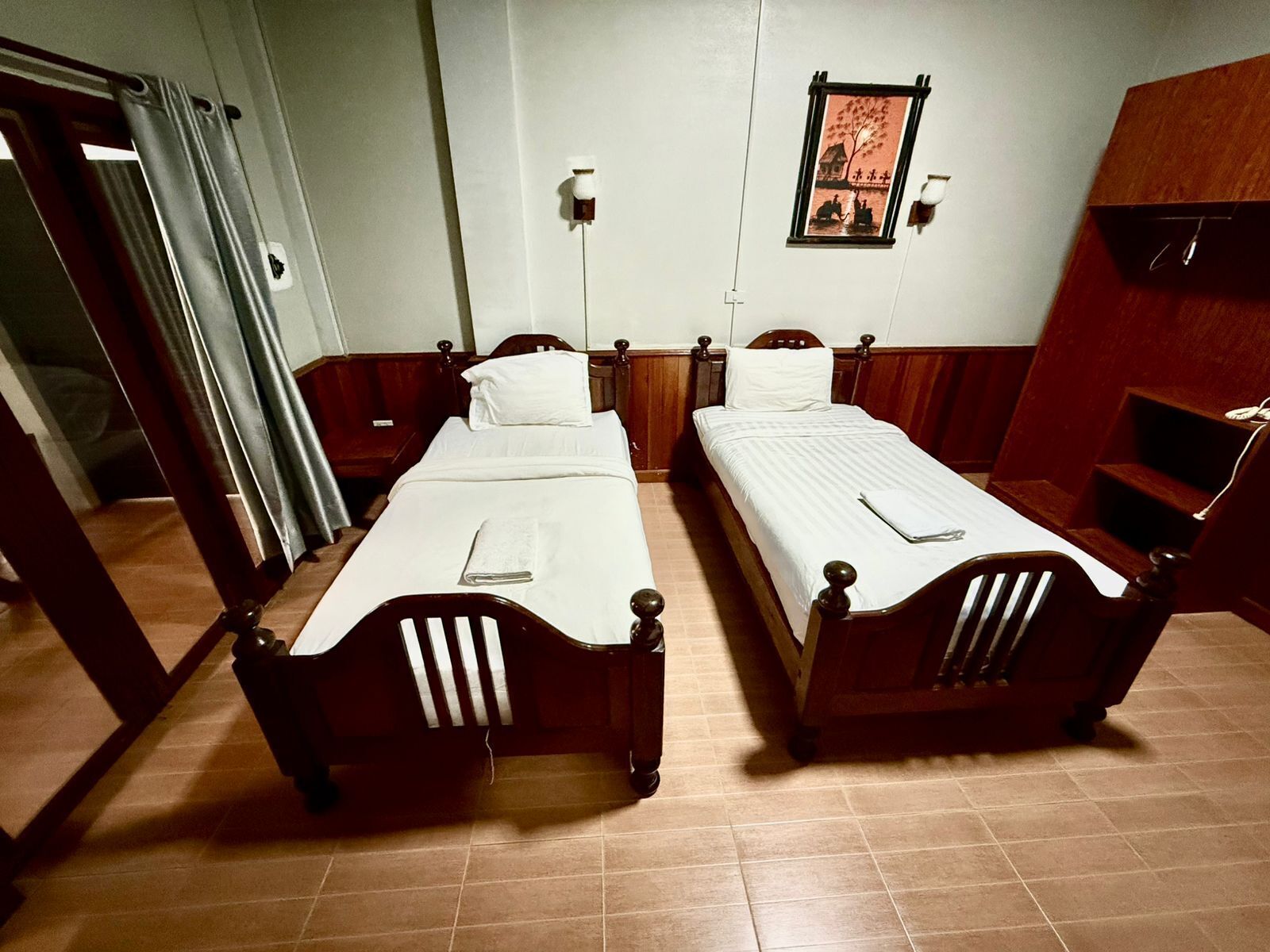 A room with two wooden beds, a small table, and a wall-mounted picture.