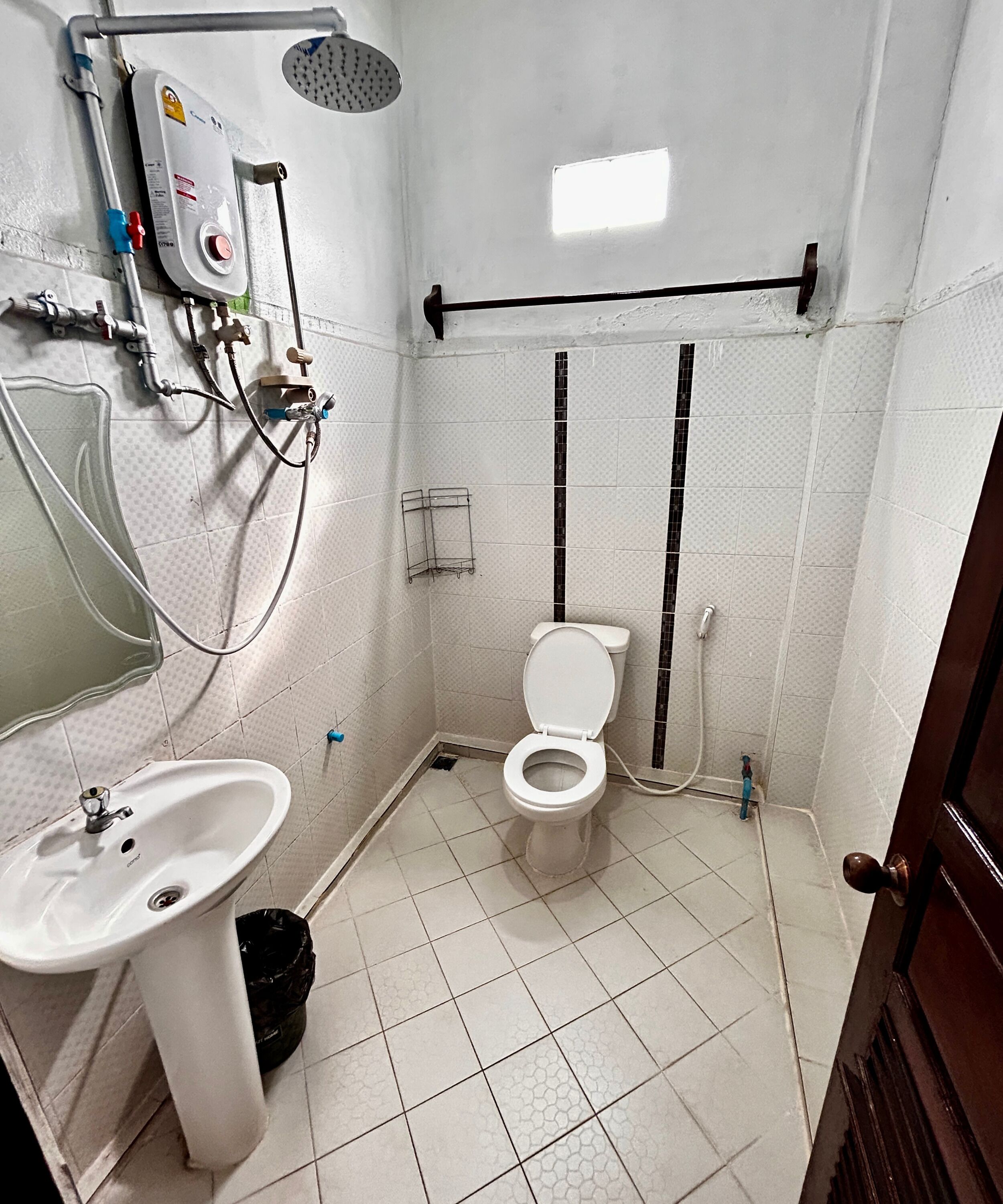 A small bathroom with a toilet, sink, shower, and a water heater.