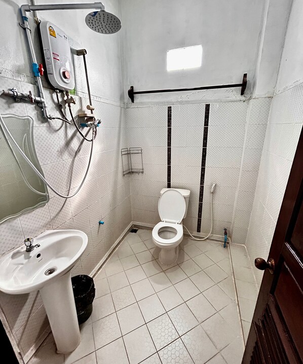 A small bathroom with a toilet, sink, shower, and a water heater. - Domon Riverside Hotel (Vang Vieng)