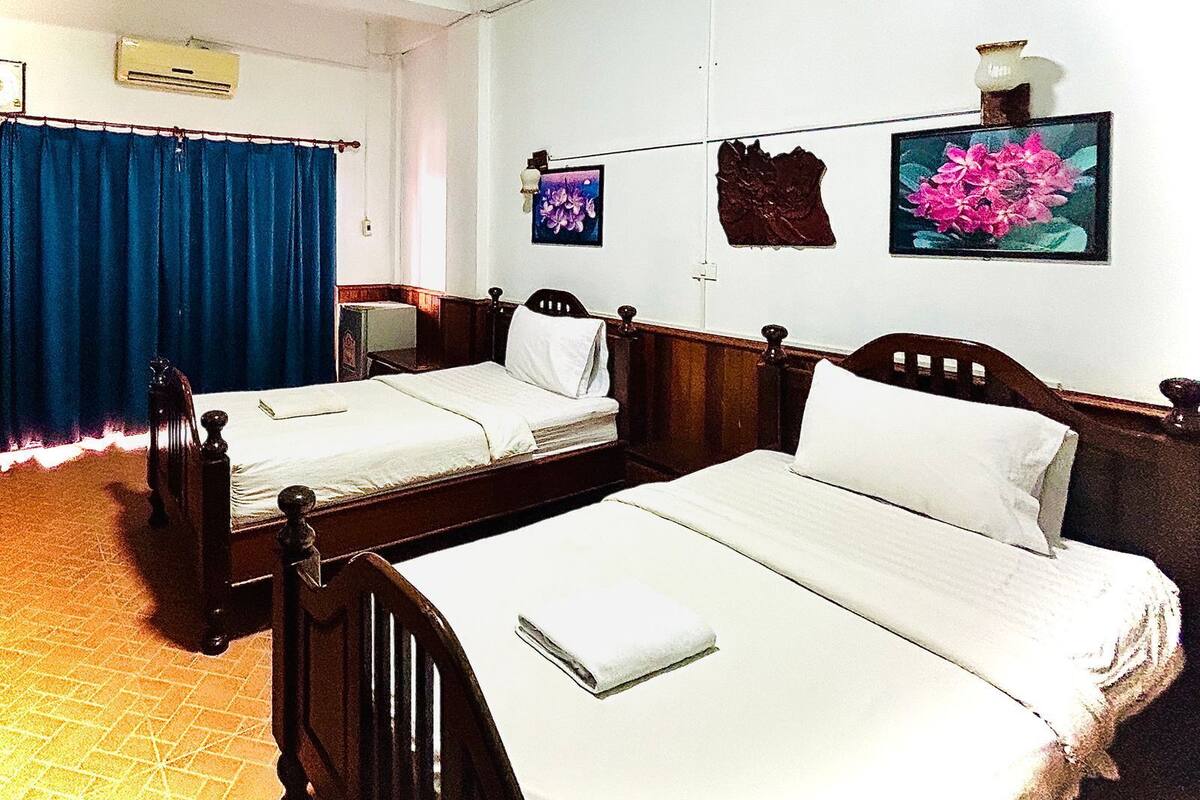 A room with two wooden beds, a blue curtain, and wall-mounted artwork.