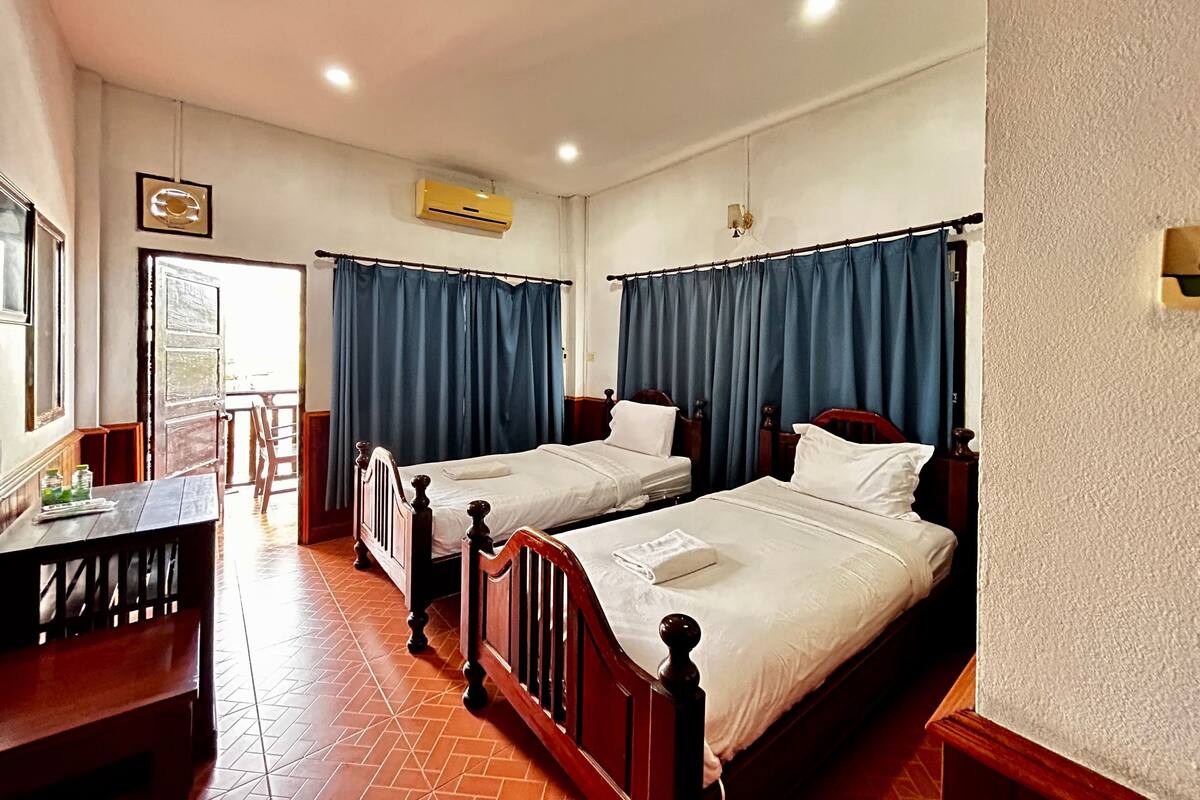 A hotel room with two wooden beds, a desk, and a chair.