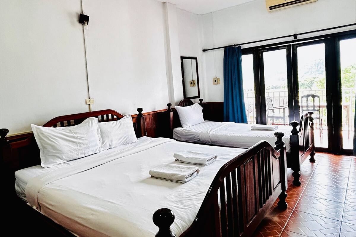A hotel room with two single beds, a large window with a view, and a balcony.
