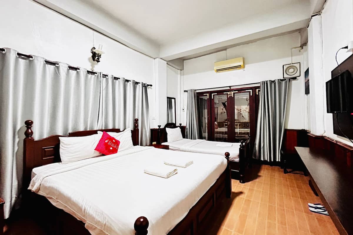 A hotel room with two beds, a TV, and a window with curtains.