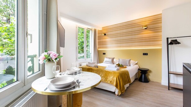 A modern hotel room with a bed, bedside table, and a window with a view of greenery. - Superb studio - 2P - Beaugrenelle / Tour Eiffel (Paris)