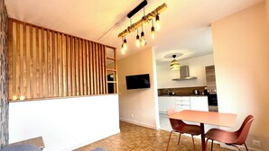 Una sala de estar moderna con un separador de listones de madera, un sofá gris y un comedor con mesa y sillas.