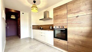 Una cocina moderna con horno empotrado, un mueble de madera y una lámpara colgante.