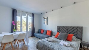 A modern bedroom with a bed, a sofa, a dining table, and chairs.