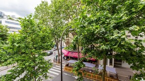 A street view with a café under a pink awning, surrounded by trees and buildings. - Cosy Studio - Beaugrenelle parc des expositions 4 (Paris)