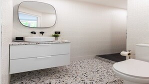 A bathroom with a white vanity, a round mirror, a sink, and a toilet. - Cosy Studio - Beaugrenelle parc des expositions 4 (Paris)