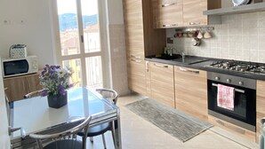 Een moderne keuken met houten kastjes, een gasfornuis en een eethoek met een tafel en stoelen.