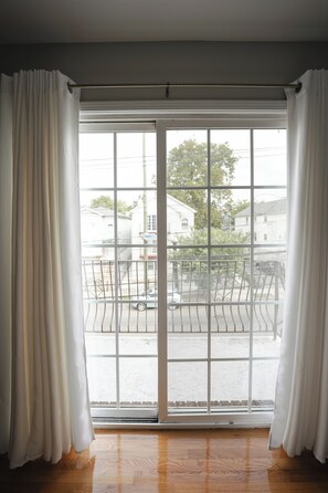 Ein Zimmer mit einer großen Schiebeglastür, die auf einen Balkon führt.