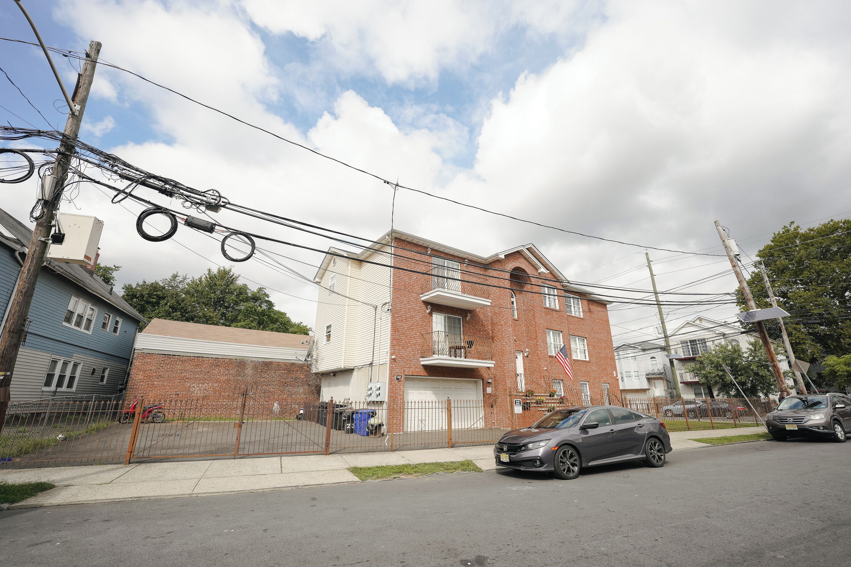 A residential building with a brick facade, a garage, and a fenced yard.