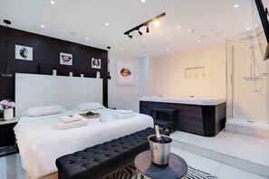 Relax in a spacious room with a large bed, seating area, and jacuzzi.