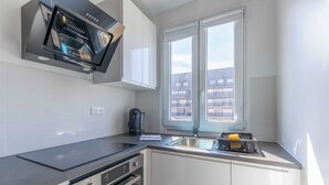 Una cocina moderna con horno integrado, cafetera y lavamanos.
