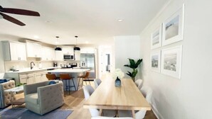 A modern kitchen with white cabinets, a wooden dining table, and a ceiling fan. - Magnolia Estate – 3 Private Quarters, Walk to Sites (Savannah)