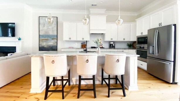 A modern kitchen with white cabinetry, a central island with bar stools, stainless steel appliances, and pendant lighting. - Magnolia Estate – 3 Private Quarters, Walk to Sites (Savannah)