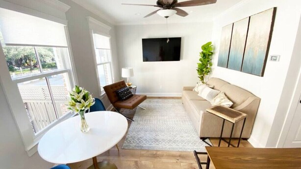 A modern living room with a round white table, blue chairs, a brown sofa, and a beige couch.