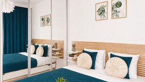 Un dormitorio moderno con una cama grande, un espejo y una bandeja con fruta y vino sobre la cama.