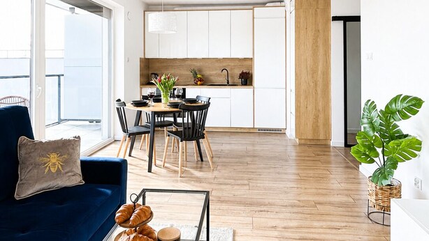 Una sala de estar moderna con un sofá, una mesa de centro y vistas a una cocina y comedor.