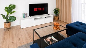 Una sala moderna con una televisión de pantalla plana, un sofá, una mesa de centro y una planta en maceta.
