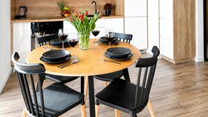 Un área de comedor moderna con una mesa redonda, sillas negras y un jarrón decorativo con flores.