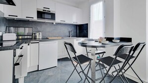 A modern kitchen with white cabinets, a black countertop, and a round dining table with four chairs.