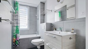 A modern bathroom with a bathtub, toilet, and vanity with a mirror.