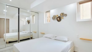 Ein Schlafzimmer mit einem großen Bett, einer Schiebetür aus Glas, einem kleinen Fenster und einer Wanddekoration.