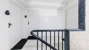 A clean, modern hallway with white walls, black railings, and numbered doors. - Comfortable Studio for 2 people - Puteaux (Puteaux)